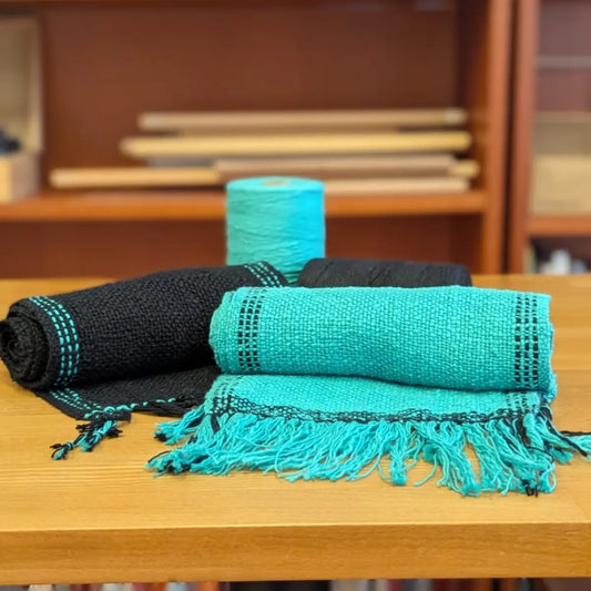 Zwei handgewebte Schals in Türkis und Schwarz mit Cotton Slub Garn auf Holztisch – Webprojekt Gatterkammrahmen