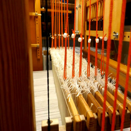 Orange Texsolv Schlaufenschnur mit weißen Clips in einem Webstuhl montiert – für präzise Schaftbindung